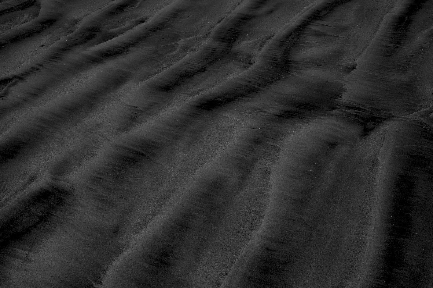 Black and white photo of waves in the sand